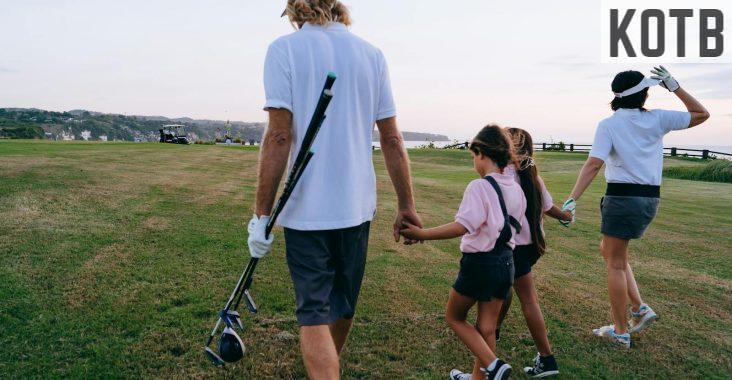 Man in White Polo Shirt and Shorts Holding Golf Clubs