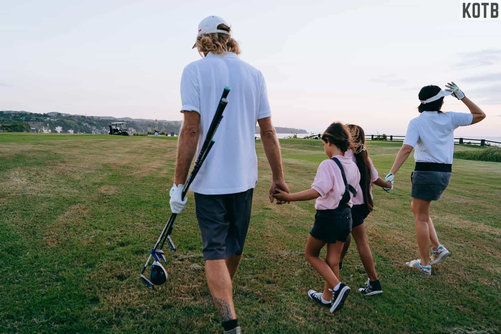 Man in White Polo Shirt and Shorts Holding Golf Clubs