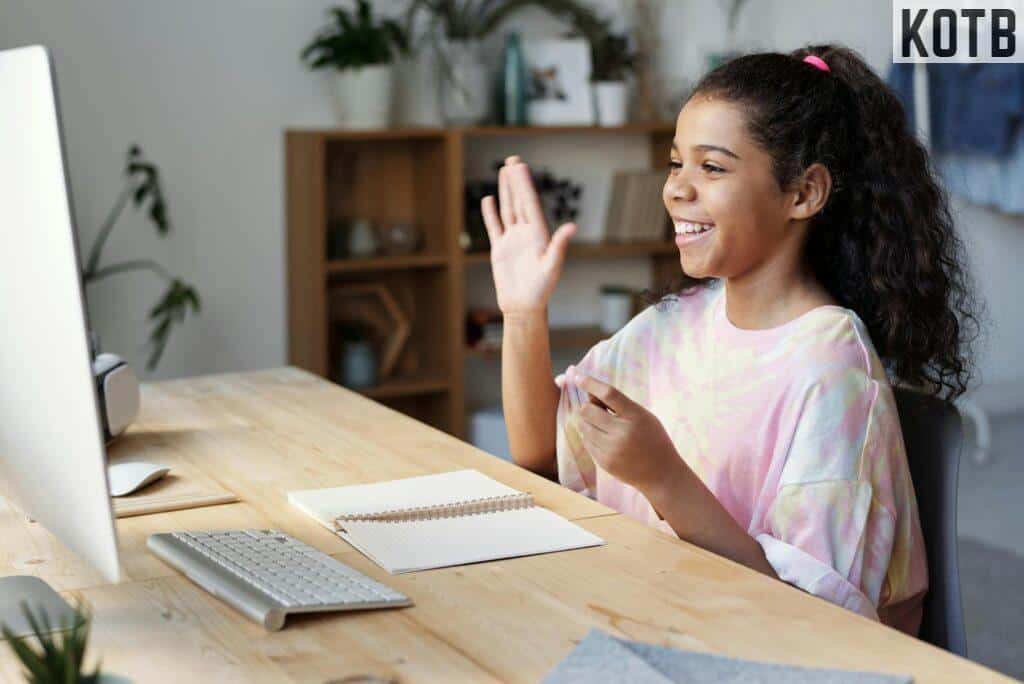 Woman in Pink Shirt Sitting by the Table While Smiling