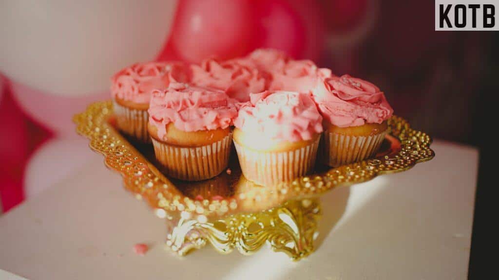 a plate of cupcakes with pink frosting on them