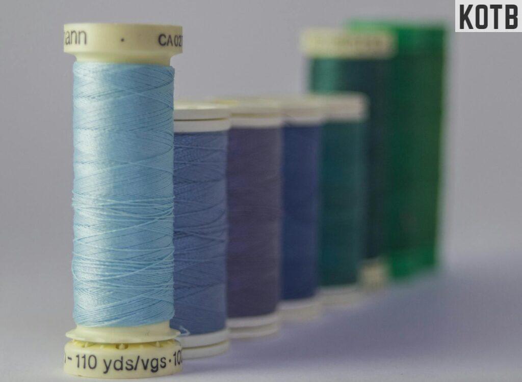 Close-up of colorful sewing thread spools aligned indoors, showcasing vivid hues and textures.