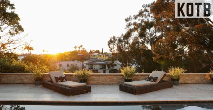 a pool with two lounge chairs and a view of a house