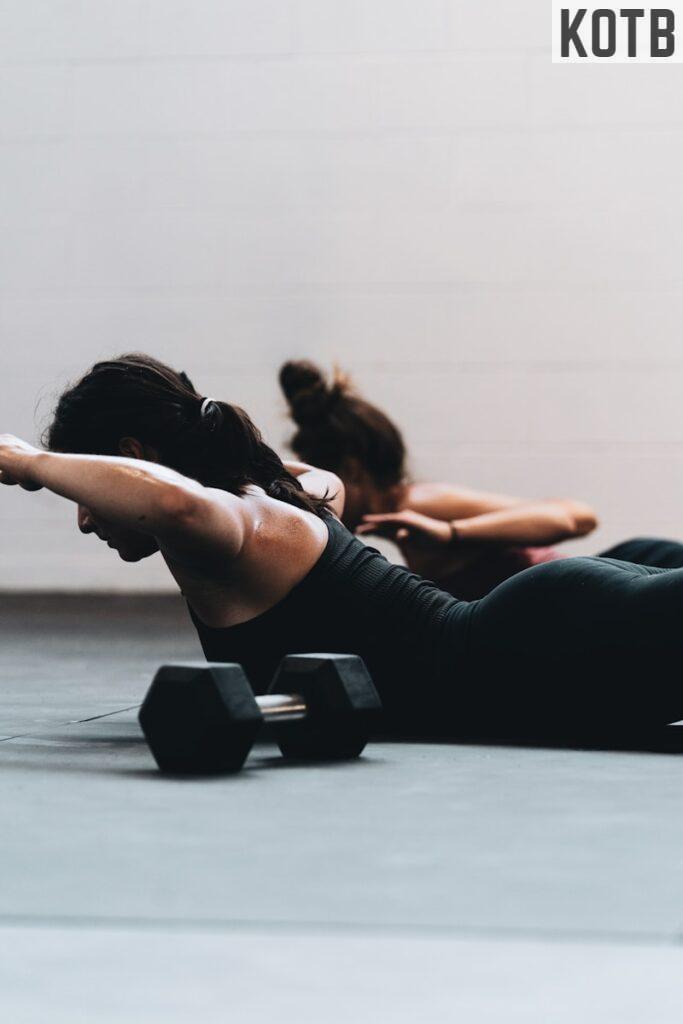 woman in black tank top and black leggings lying on black floor