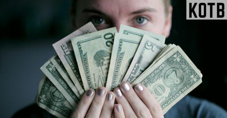 person holding fan of U.S. dollars banknote