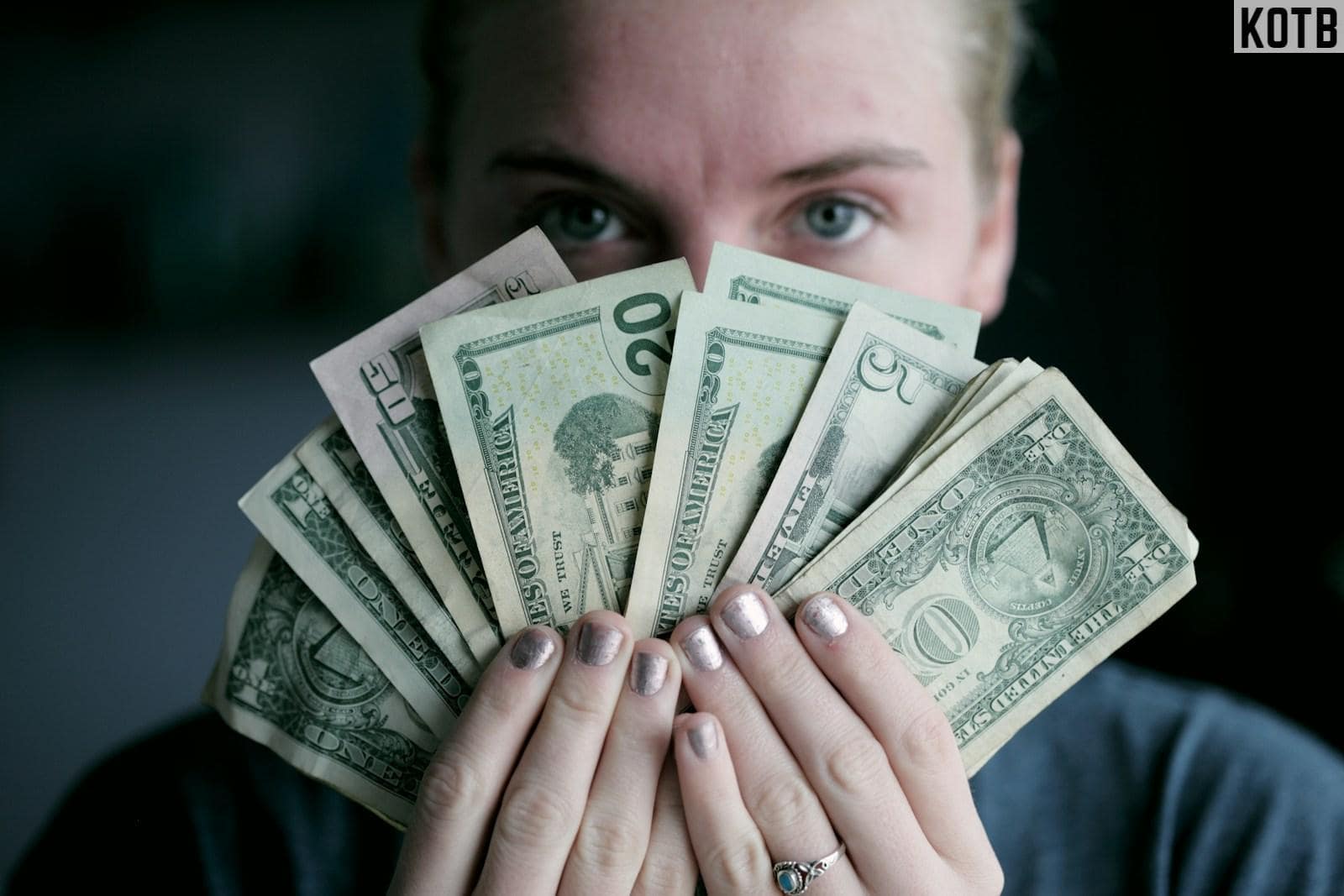person holding fan of U.S. dollars banknote